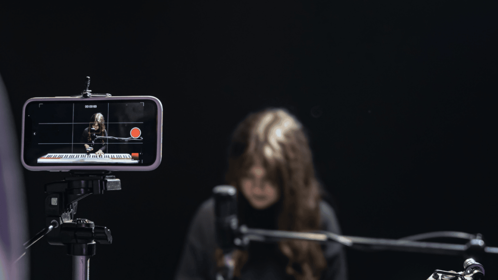 Smartphone filming a pianist in a studio setting for a video production.