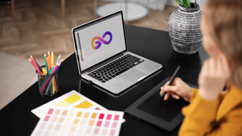 Designer working on a laptop and tablet, creating Ipoh Logo Design.