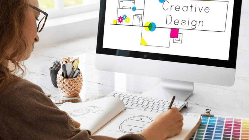 Designer sketching ideas with 'Creative Design' on screen, highlighting Logo Design Malaysia.